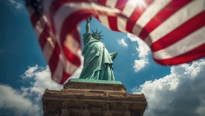 Papier peint photo Statue de la Liberté Statue of liberty against a cloudy sky with an american flag waving in the foreground view  © Abuzar