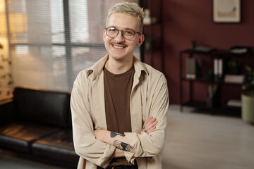 Portrait of self-confident gen Z Caucasian man standing with arms crossed, smiling at camera while...