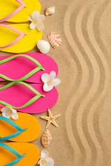Colorful flip flop sandals arranged on a sandy beach with seashells and starfish