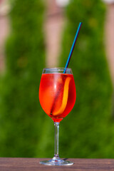 Aperol spritz cocktail in wine glass on a nature background. Classic italian aperitif aperol spritz cocktail with slice of orange. Closeup. Summer refreshing drink with sunlight