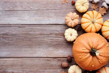 Fall side border of muted tone pumpkins and natural decor. Top view on a rustic wood background...