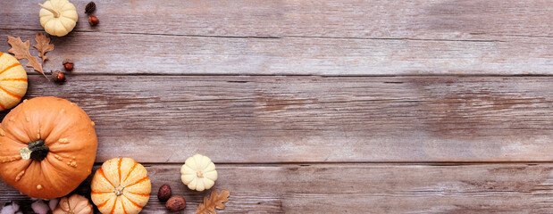Fall corner border of muted tone pumpkins and natural decor. Overhead view on a rustic wood banner...
