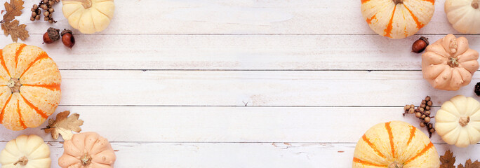 Autumn double border of pumpkins, golden leaves and natural decor. Top view on a white wood banner background with copy space.