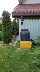 Water storage tank and yellow container beside house in garden  