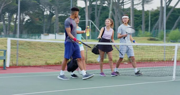 Diverse friends entering court carrying racquets, balls, chatting, passing water, planning play