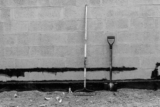 Yard tools leaning against wall black and white
