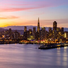Obraz premium City skyline at sunset with glowing lights and dramatic sky