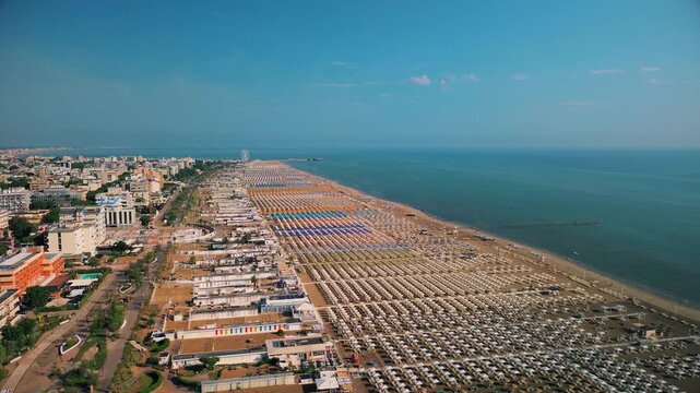 Aerial view of large equipped sandy beaches. Umbrellas and sun loungers for vacationers by the sea. Vacation on the Adriatic Sea. Ferris wheel. Traveling on Europe. Vacation in Italy Rimini 21.07.2025