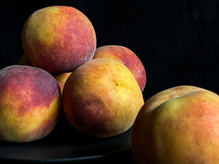 Fresh peaches and a glass of juice on a dark background. Still life with ripe fruits and refreshing drink