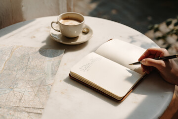 Notebook and coffee on a table alongside a map in a cozy cafe during the afternoon
