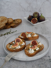 Vertical Close Up of Fig and Goat Cheese Toasts with White Plate and Gray Background