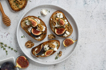 Close Up Horizontal Fig Toasts with Goat Cheese and Figs on White Plate and Gray Background