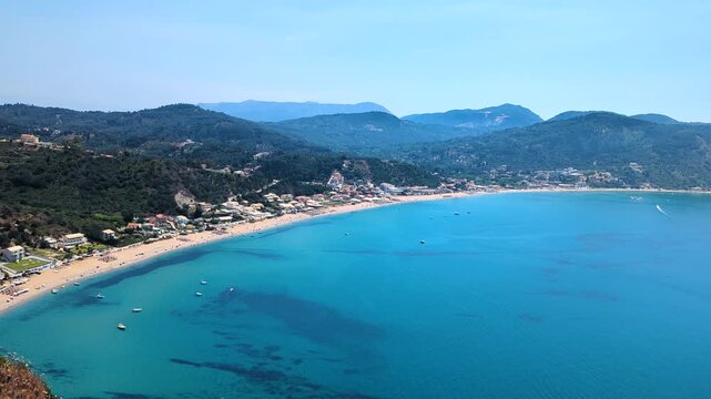 Wonderful view from above of azure waters of Ionian Sea and wide beach of Agios Georgios village located at foot of mountain. Beautiful place for beach holiday. Corfu island. Greece.
