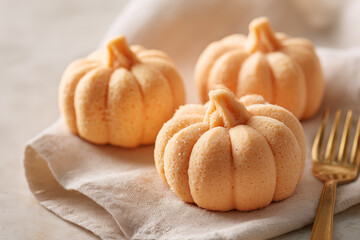 Seasonal pumpkin-shaped treats displayed on a linen cloth with a golden fork beside them