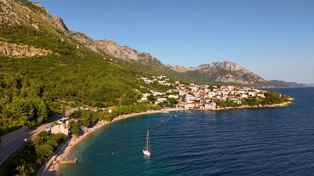 Golden hour aerial of Igrane Croatia curving beach red rooftops Adriatic horizon and dramatic limestone mountains of Biokovo