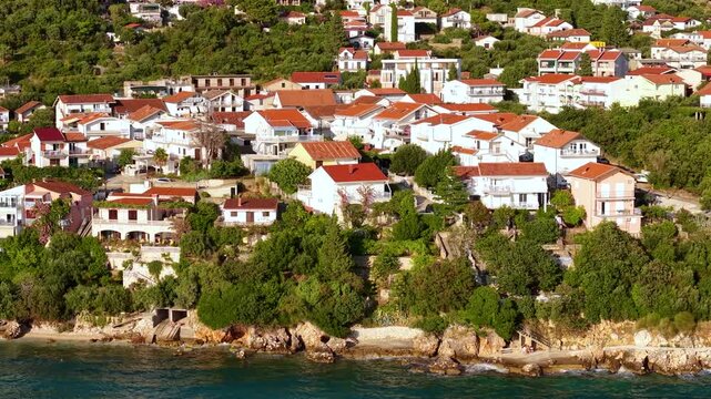 Golden hour drone view of Igrane Croatia with pebble shore pine forest Adriatic horizon and tranquil village