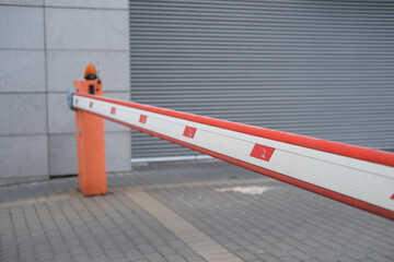 Automatic parking barrier gate with red and white stripes, used for vehicle entry control at...