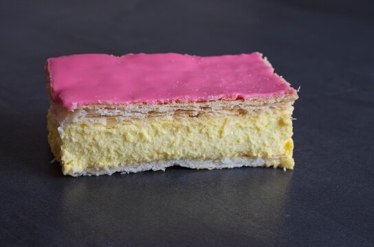 A Dutch delicacy on a dark kitchen counter. A pastry that consists of two layers of puff pastry, with the top layer glazed, and pastry cream in between.