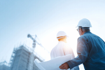 Two architects review blueprints on a construction site, symbolizing collaboration, progress, and innovation. Ideal for real estate, engineering, or project management themes.