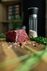 close up of a piece of fresh beef on a wooden cutting board. farm fresh meat with coarse salt and herbs on the table