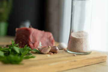 close up of a piece of fresh beef on a wooden cutting board. farm fresh meat with coarse salt and...