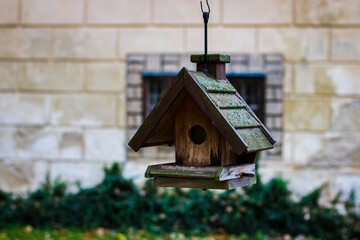 Wooden birdhouse hanging outdoors with blurred background, photographed at Hrubý Rohozec Chateau, Czech Republic.