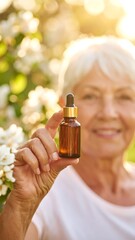 Fototapeta premium Senior woman holding small amber bottle of serum in garden