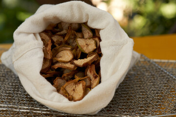 Close-up of pear chips in a canvas bag on a metal dehydrator rack.