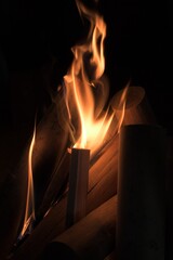 A fire of neat, cleaned wood flares up in the darkness. The flames spread to new logs