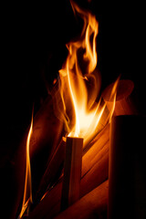 A fire of neat, cleaned wood flares up in the darkness. The flames spread to new logs