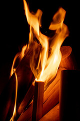 A fire of neat, cleaned wood flares up in the darkness. The flames spread to new logs