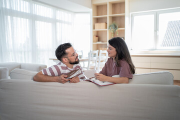 Couple relaxing on sofa reviewing photo albums and talking at home