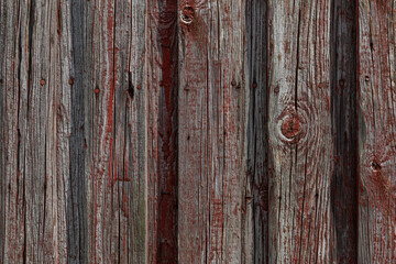 Weathered wooden wall with faded red paint, rustic vertical planks 

