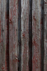 Weathered wooden wall with faded red paint, rustic vertical planks 
