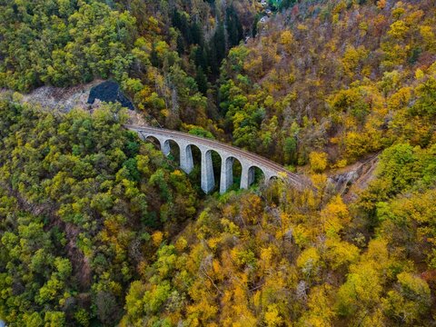 Žampach Railway Viaduct in J&iacute;lov&eacute; u Prahy, Czech Republic. Aerial view of the historic stone bridge surrounded by forest in vibrant autumn colors.