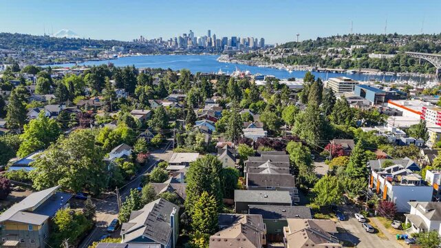 Flying over a Seattle neighborhood with a view of Lake Union and downtown district in the distance on a sunny summer day