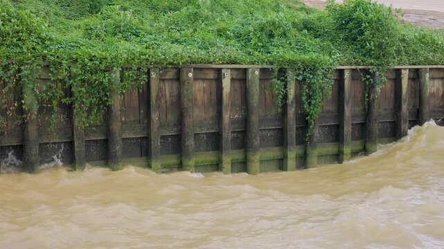 heavy waves pounding a wooden bulkhead or retaining wall