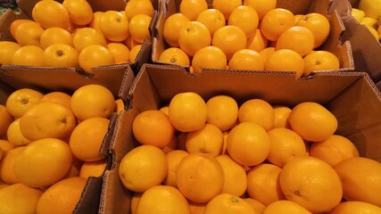 Yellow tomatoes and lemons in cardboard boxes at a shopping mall.