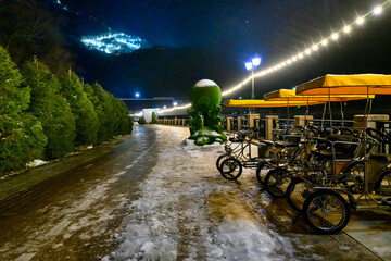 A night shot of a ski resort street, with four-wheeled pleasure bikes in a row, against the...