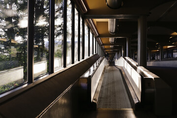 Empty moving walkway in modern building interior. Long perspective view with windows and sunlight...