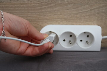 The girl inserts the charger into a white extension cable

