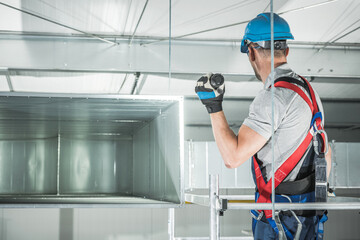 Caucasian HVAC Worker Installs Ventilation Duct in a Construction Site With Safety Gear