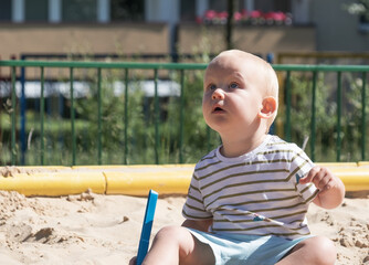 Baby boy playing in sandbox, little funny European boy, blond 1.5 years old, having fun on...