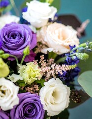 Fototapeta premium Close-up of a bouquet featuring purple, white, and blush roses, complemented by other flowers and greenery