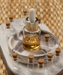 A bottle with a pipette surrounded by small empty bottles with corks. The objects are arranged on a...