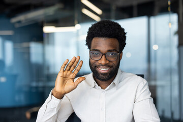 Friendly professional waving and smiling in a modern office environment