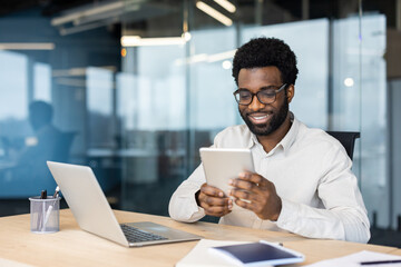 Professional man smiling while working on tablet in modern office environment