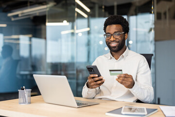 Obraz premium Man Shopping Online with Smartphone and Credit Card in Modern Office