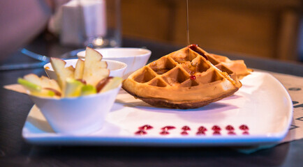 A plate of delicious, warm, freshly baked waffles served with a selection of fresh sliced fruits...