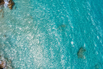 Aerial view of Voulisma Beach in Crete, showcasing turquoise waters, submerged rocks, sunlight...